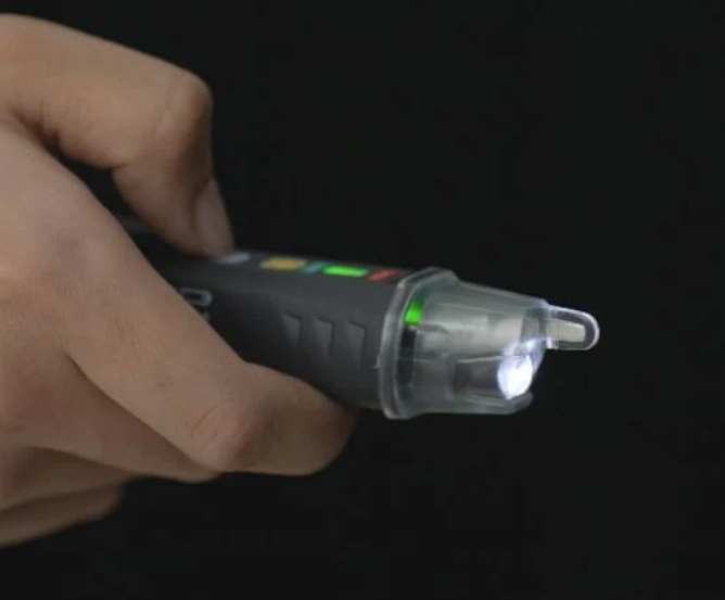 Hand holding a device with a light on a dark background