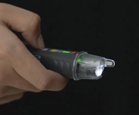 Hand holding a device with a light on a dark background